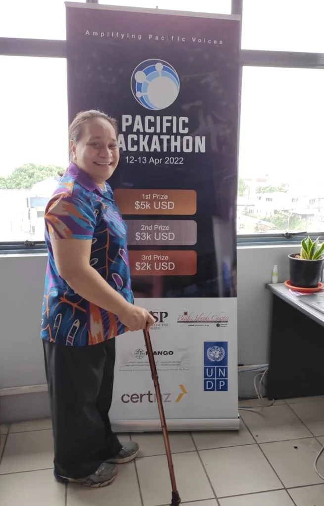 A woman stands in front of a Pacific Hackathon sign